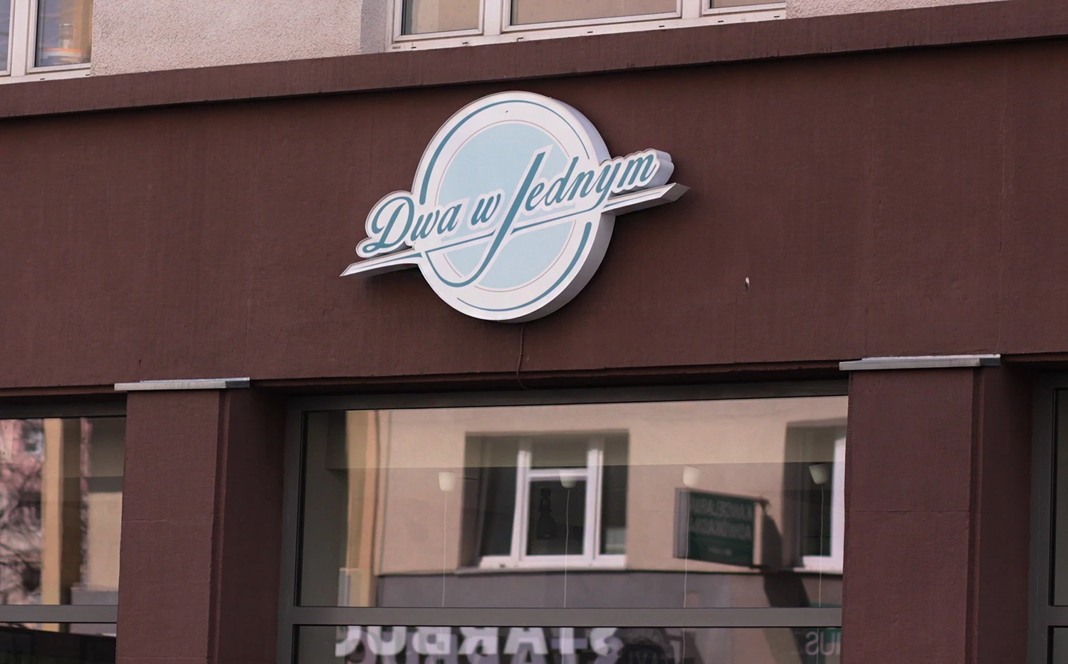 Two in one — Lit lightbox with brand logo mounted on a building facade