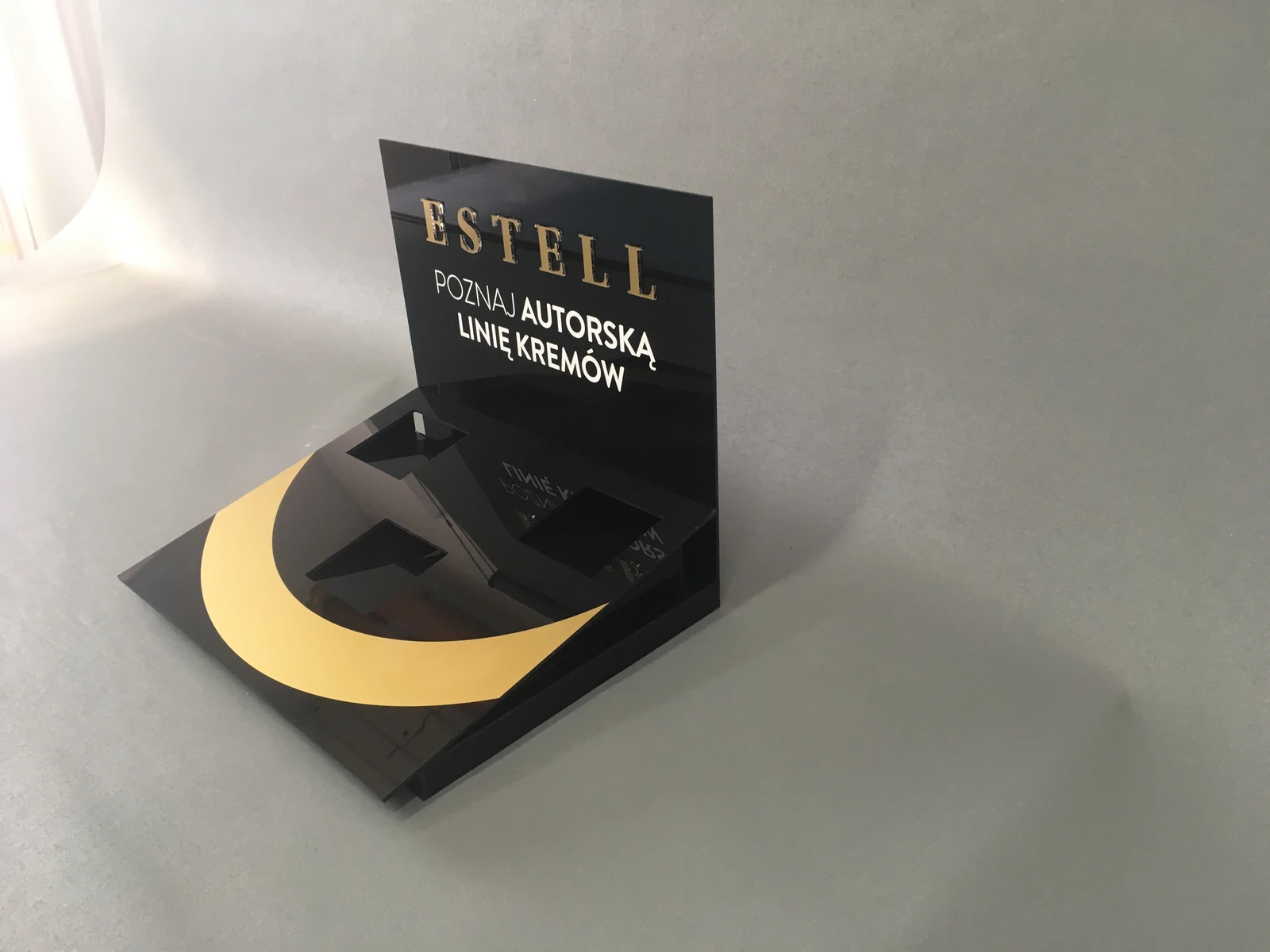 ESTELL — Tabletop display from black plexi from yellow element half-moon, sign information from tekstem of linii creams